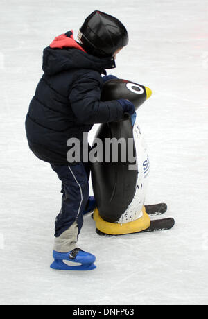 Essen, Deutschland. 26. Dezember 2013. Ein Junge hält eine Pinguin Figur auf eine Eisbahn am Zollverein industrieller Komplex in Essen, Deutschland, 26. Dezember 2013. Foto: CAROLINE SEIDEL/Dpa/Alamy Live News Stockfoto