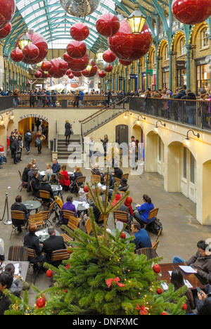 Weihnachtsschmuck mit Straßenmusikern und Diners in Covent Garden, London. Stockfoto