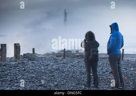 Aberystwyth, Wales, UK. 27 Dezember 2013.Gale Winde batter die walisische Küste und bei Flut massive Wellen brechen sich am Meer front in Aberystwyth. Ein paar Uhren und Foto Wellen brechen über das Positionslicht auf der Hafenmole. Bildnachweis: atgof.co/Alamy Live News Stockfoto