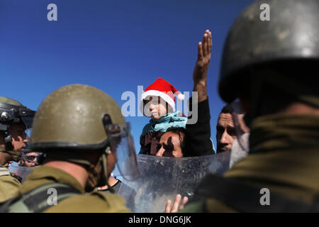 Bethlehem, West Bank Stadt Bethlehem. 27. Dezember 2013. Eine palästinensische Demonstranten Gesichter mit israelischen Soldaten während einer Demonstration gegen Israels umstrittene Trennungsmauer in Al-Maasarah, einem Dorf in der Nähe der West Bank Stadt Bethlehem, 27. Dezember 2013. © Luay Sababa/Xinhua/Alamy Live-Nachrichten Stockfoto