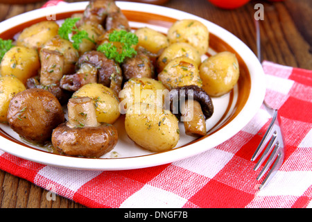 Braune Champignons mit Rosmarin-Kartoffeln auf Holz Hintergrund, Nahaufnahme Stockfoto