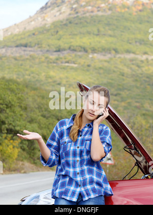 Junge Frau in der Nähe von kaputten Auto per Telefon sprechen braucht Hilfe Stockfoto