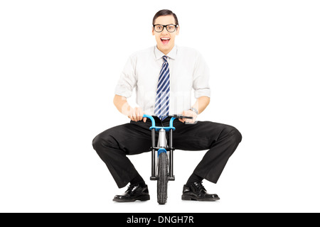 Lächelnde junge Geschäftsmann mit Krawatte auf dem kleinen Fahrrad Stockfoto