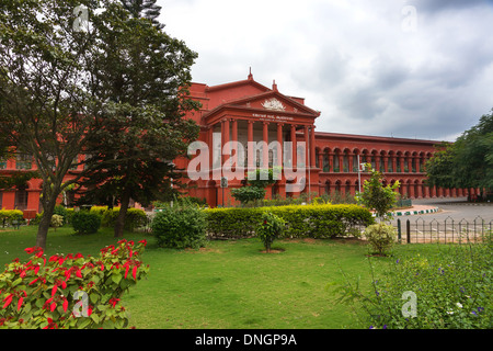 Blick von der Straße auf rotem Backstein-Gebäude bekannt als Attara Kacheri, der Sitz des High Court und Gärten in Bangalore. Stockfoto