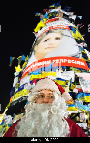 Kiew, Ukraine, 28. Dezember 2013. Weihnachten und Silvester Feier bei pro-europäischen Protest in Kiew. Der Weihnachtsmann grüßt Menschen in der Nähe von Euromaidan Weihnachtsbaum mit einem Poster von gefangengesetzten Oppositionsführer Yulia Tymoshenko. Bildnachweis: Oleksandr Rupeta/Alamy Live-Nachrichten Stockfoto