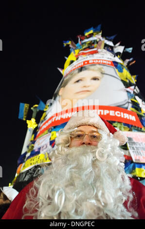 Kiew, Ukraine, 28. Dezember 2013. Weihnachten und Silvester Feier bei pro-europäischen Protest in Kiew. Der Weihnachtsmann grüßt Menschen in der Nähe von Euromaidan Weihnachtsbaum mit einem Poster von gefangengesetzten Oppositionsführer Yulia Tymoshenko. Bildnachweis: Oleksandr Rupeta/Alamy Live-Nachrichten Stockfoto