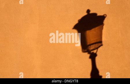 schwarze Schatten des alten Straßenlaterne auf gelbe Wand Closeup Muster Stockfoto