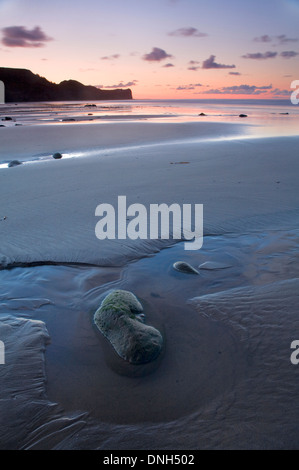 Die zurückweichenden Flut lässt einen Pool um einen Kieselstein in den Sand am Strand von Whitbys, North Yorkshire bei Sonnenuntergang. Stockfoto