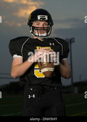 American High School Football-Spieler in Uniform mit Helm und Fußball. Stockfoto