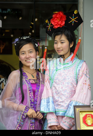 Chinesische Mädchen gekleidet in traditionellen Kleidern und Kopfbedeckungen. Stockfoto