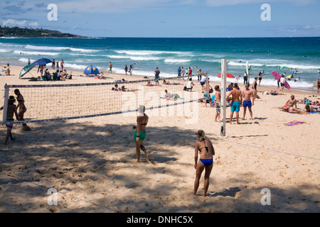 Frauen spielen Beachvolleyball am Manly Beach, Sydney, Australien, mit Menschen, die sich im Sand sonnen Stockfoto