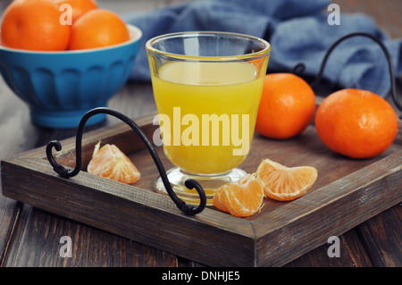 Mandarine Saft im Glas mit frischen Früchten auf hölzernen Hintergrund Stockfoto