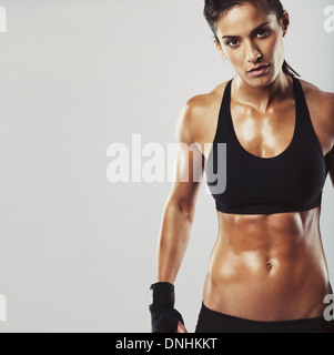 Bild eines Fitness-Modells auf grauem Hintergrund. Junge Frau Bodybuilder mit muskulösen Körper, Blick in die Kamera mit Exemplar Stockfoto