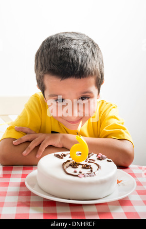 Sechs Jahre alter Junge schaut Geburtstagstorte Stockfoto