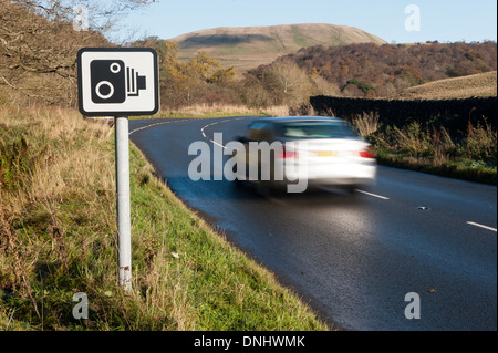 Auto auf der Landstraße, vorbei an einer Geschwindigkeit Kamera Warnschild. Cumbria, UK Stockfoto