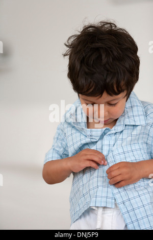 Kleiner Junge lernt, seine Knöpfe anbringen Stockfoto