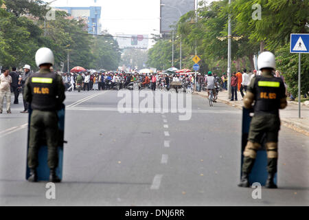 Phnom Penh, Kambodscha. 31. Dezember 2013. Anti-Polizei Wache während Hunderte von Textilarbeiterinnen Sperrung einer Straße vor dem Ministerium auf Nachfrage höheren Lohn in Phnom Penh, Kambodscha, 31. Dezember 2013. Kambodscha am Dienstag beschlossen, der monatliche Mindestlohn in der Bekleidungsbranche auf 100 US-Dollar von Februar ab von der aktuellen 80 US-Dollar zu erhöhen, sagte eine Ankündigung von Arbeitsminister Ith Samheng unterzeichnet. Bildnachweis: Phearum/Xinhua/Alamy Live-Nachrichten Stockfoto