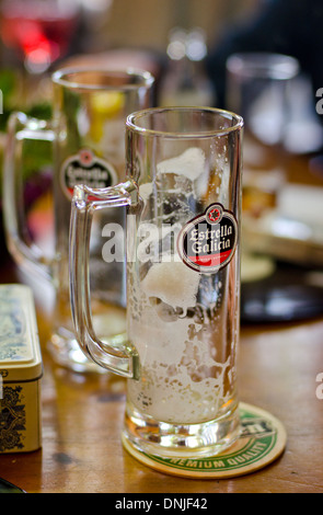 Leeres Glas Estrella Galicia eine Marke helle Lagerbier aus Spanien auf einer Achterbahn. Stockfoto