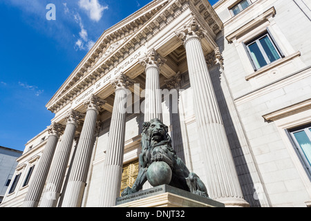 Bronze lion Skulptur Blick auf die beeindruckende Säulen getragenen Eingang des Congreso de los Diputados (Abgeordnetenkammer), Plaza De Las Cortes, Madrid, Spanien Stockfoto