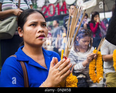 Bangkok, Thailand. 31. Dezember 2013. Eine Frau betet am Erawan-Schrein auf Vorabend des neuen Jahres in Bangkok. Hunderttausende von Menschen packen in der Ratchaprasong Kreuzung in Bangkok für die Stadt jährliche Silvester Countdown. Viele Thais gehen die Erawan-Schrein und Wat Pathum Wanaram nahe der Kreuzung zu beten und Verdienst machen. Bildnachweis: Jack Kurtz/ZUMAPRESS.com/Alamy Live-Nachrichten Stockfoto