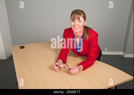 Frau in einer roten Jacke sitzen in einem Büro in ein leerer Schreibtisch Stockfoto