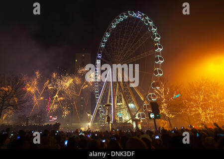 Happy New Year Feiern, während die Massen Vergnügungsfahrten mit Lichtern in Manchester, Großbritannien, genießen Januar 2014. In diesem Jahr veranstaltete Piccadilly Gardens zum ersten Mal die privat gesponserten Silvesterfeiern und Feuerwerke von Manchester. Die Veranstaltung beinhaltete eine 10-minütige Feuerwerksvorstelle, ein Riesenrad, einen Park, einen Spaß, einen Himmel, Unterhaltung, Unterhaltung, Reisen, Stadt, Karneval, Fair, reiten, blau, Karussell, Attraktion, Freizeit, Festival, Nachtkreis. Silvester Big Wheel fährt auf der 60m-hohen, 42-Pod-Spinning-Fahrt bis 1am. Stockfoto