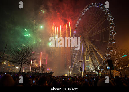 Happy New Year Feiern, während die Massen Vergnügungsfahrten mit Lichtern in Manchester, Großbritannien, genießen Januar 2014. In diesem Jahr veranstaltete Piccadilly Gardens zum ersten Mal die privat gesponserten Silvesterfeiern und Feuerwerke von Manchester. Die Veranstaltung beinhaltete eine 10-minütige Feuerwerksvorstelle, ein Riesenrad, einen Park, einen Spaß, einen Himmel, Unterhaltung, Unterhaltung, Reisen, Stadt, Karneval, Fair, reiten, blau, Karussell, Attraktion, Freizeit, Festival, Nachtkreis. Silvester Big Wheel fährt auf der 60m-hohen, 42-Pod-Spinning-Fahrt bis 1am. Stockfoto