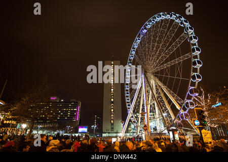 Happy New Year Feiern, während die Massen Vergnügungsfahrten mit Lichtern in Manchester, Großbritannien, genießen Januar 2014. In diesem Jahr veranstaltete Piccadilly Gardens zum ersten Mal die privat gesponserten Silvesterfeiern und Feuerwerke von Manchester. Die Veranstaltung beinhaltete eine 10-minütige Feuerwerksvorstelle, ein Riesenrad, einen Park, einen Spaß, einen Himmel, Unterhaltung, Unterhaltung, Reisen, Stadt, Karneval, Fair, reiten, blau, Karussell, Attraktion, Freizeit, Festival, Nachtkreis. Silvester Big Wheel fährt auf der 60m-hohen, 42-Pod-Spinning-Fahrt bis 1am. Stockfoto