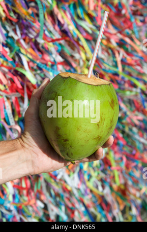 Brasilianische Hand hält Coco Gelado trinken Kokosnuss an Wand des Wunsch-Bänder in Salvador Bahia Brasilien Stockfoto