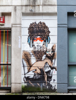 Urbane Streetart Indianerin in Maske halten haarlose Sphynx Katze - Cheshire Straße, East London, UK Stockfoto