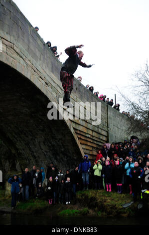 Mapleton, Derbyshire, UK. 01. January2013. Silvester-Tag-Brücke springen für wohltätige Zwecke. Teams verkleidet nahmen an der jährlichen Veranstaltung in das Dorf Mapleton Teil, beginnend mit einem Bootsrennen auf dem Fluss Dove dann ein kurzer Lauf bis zur Brücke, wo sie dann in dem Fluss Dove, sprang, schwammen zum Rand und raste bis zu der Kneipe für die Finsih, waren ein warmes Getränk und Kleider waren in Ordnung. Die Bedingungen sehr windig und schwere Regen hielt die Massen sich in diesem Jahr. Bildnachweis: Ian Francis/Alamy Live-Nachrichten Stockfoto