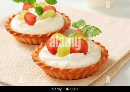 Kleine Creme Törtchen garniert mit frischen Weintrauben Stockfoto