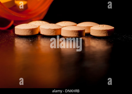 Gegossen, auf einem dunklen Tisch neben Pille Flasche Pillen. Stockfoto