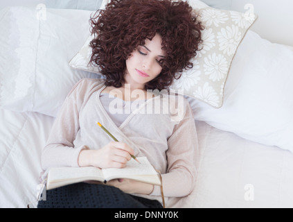 Schöne Frau im Bett schreibt Tagebuch Stockfoto