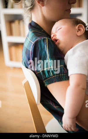 Babymädchen (2-5 Monate) schläft in Mutters Armen Stockfoto