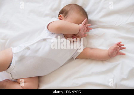 Babymädchen (2-5 Monate) am Bett liegen und Weinen Stockfoto