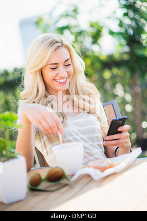 Teenager-Mädchen (16-17) Kaffee trinken und mit Handy Stockfoto