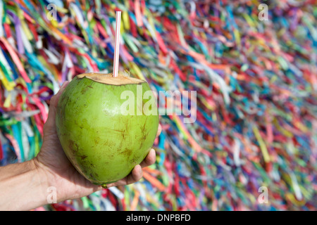 Brasilianische Hand hält Coco Gelado trinken Kokosnuss an Wand des Wunsch Bänder Bonfim Kirche in Salvador Bahia Brasilien Stockfoto