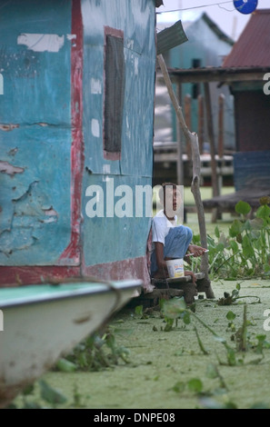 Ein Junge mit einer psychischen Erkrankung steht in seinem Pfahlbauten-Haus, umgeben von Wasser bedeckt mit Lemma Pflanzen im Kongo Mirador Stockfoto