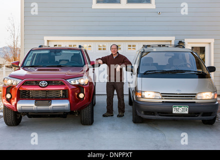 Im mittleren Alter Mann posiert mit 2014 Toyota 4Runner Trail Premium & 1996 Toyota Previa LE/SC AWD Stockfoto