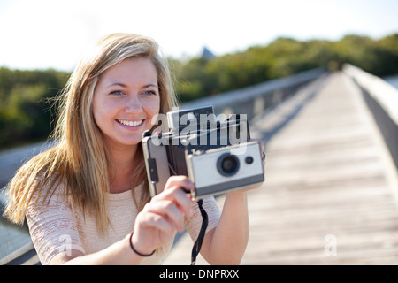 Junge Frau am Gehweg mit Kamera, USA Stockfoto