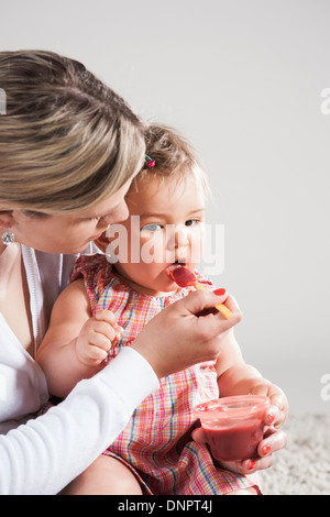 Porträt der Mutter Fütterung Tochter, Studioaufnahme Stockfoto