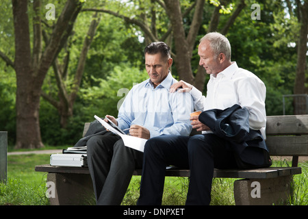 Geschäftsleute suchen bei der Arbeit am Park Bench, Mannheim, Baden-Württemberg, Deutschland Stockfoto
