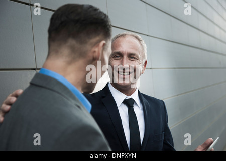 Reife Geschäftsleute vor Wand stehend, im Gespräch Stockfoto