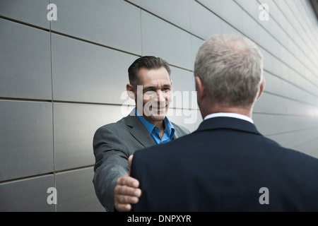 Reife Geschäftsleute vor Wand stehend, im Gespräch Stockfoto
