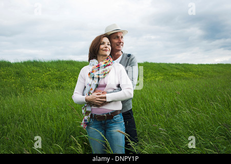 Porträt des reifes Paar stehen im Bereich des Grases, umarmen, Deutschland Stockfoto