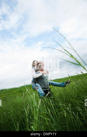 Älteres Paar im Bereich des Grases, Mann geben Huckepack Fahrt zur Frau, Deutschland Stockfoto