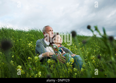 Älteres Paar sitzt im Bereich des Grases, umarmen, Deutschland Stockfoto