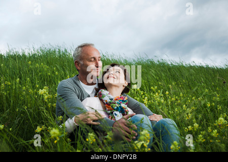 Älteres Paar sitzt im Bereich des Grases, umarmen, Deutschland Stockfoto