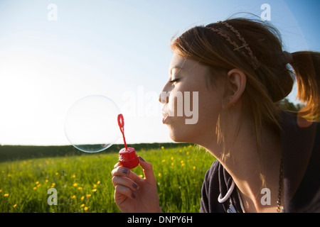 Nahaufnahme von Teenager-Mädchen bläst Seifenblasen im Feld, Deutschland Stockfoto